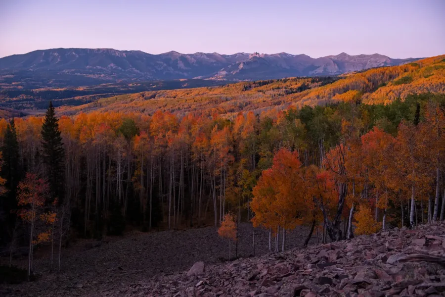 Soft twilight settles over The Castles and vibrant red and gold fall aspens in the Colorado Rockies.
