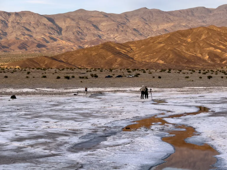 Night photography workshop photographers capturing the salt flats and water channels with the Panamint Range behind them.
